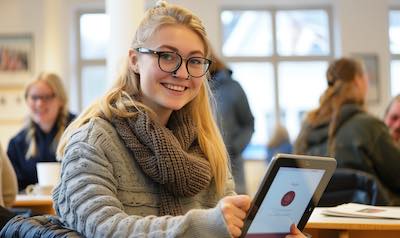 Studentin lernt auf Tablet mit einem Schwedisch B1 Sprachkurs für Fortgeschrittene